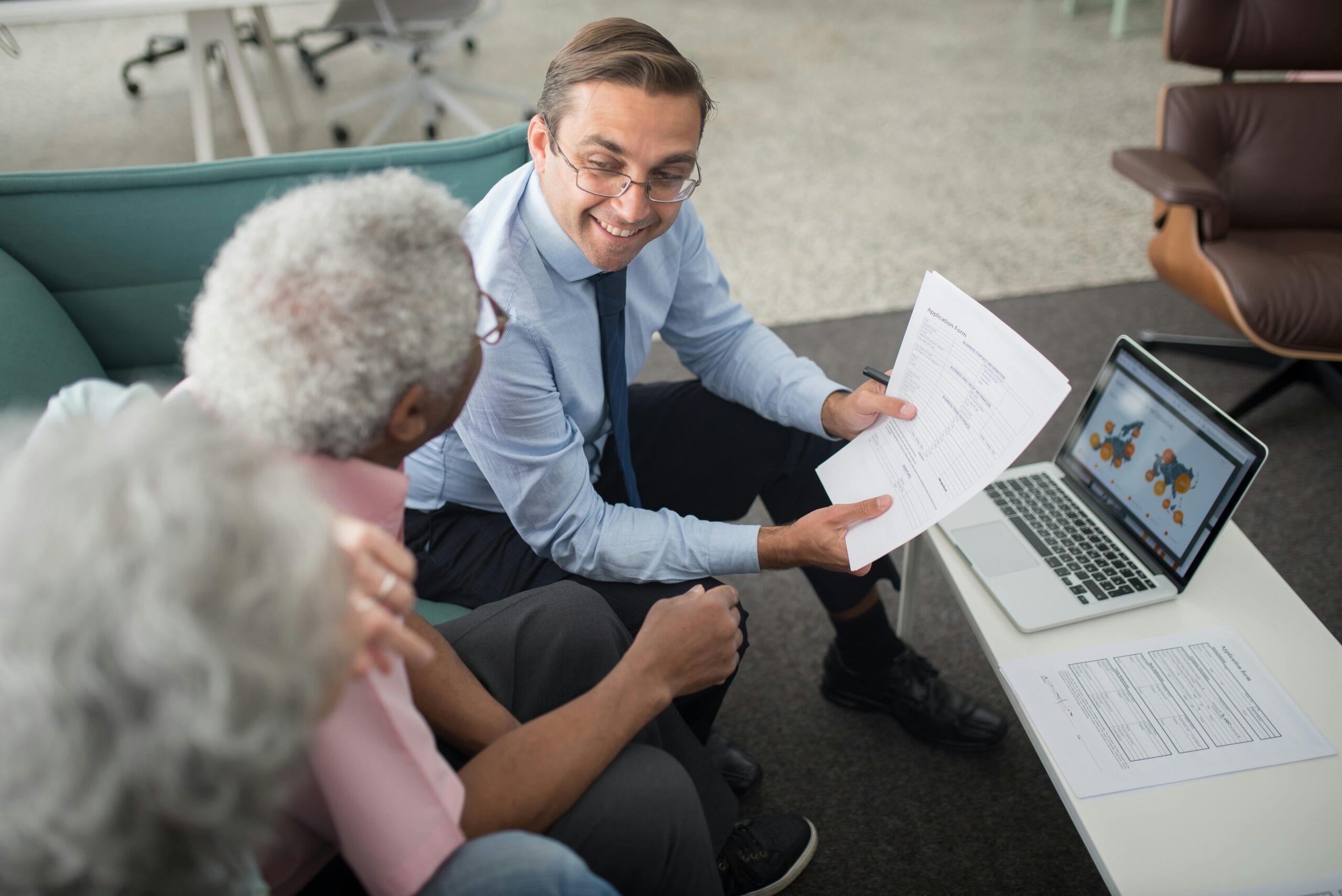 Man and two women discussing life insurance at a table with a laptop.