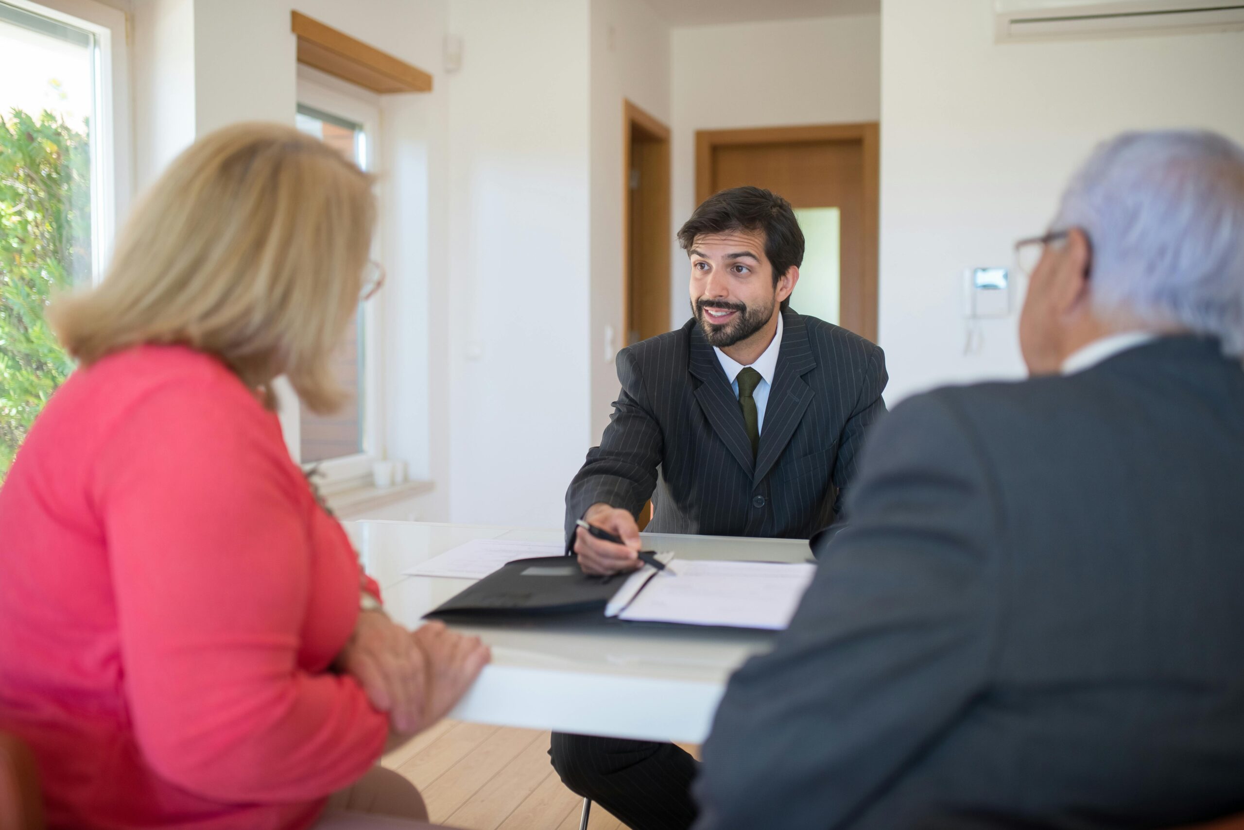 Man in a suit converses about Whole Life Insurance with two elderly people.